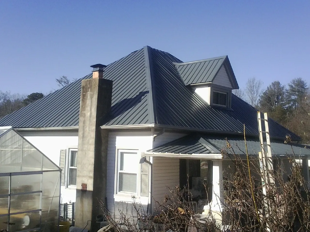 Dark blue standing seam metal roof on a white farmhouse with dormer — Slate & Tile Roof Repair by Roofing Brothers in Idyllwild