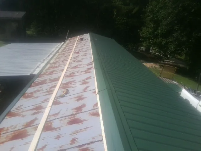 Old rusted panels beside newly installed green metal roofing — Wind Damage Roof Repair by Roofing Brothers in Idyllwild