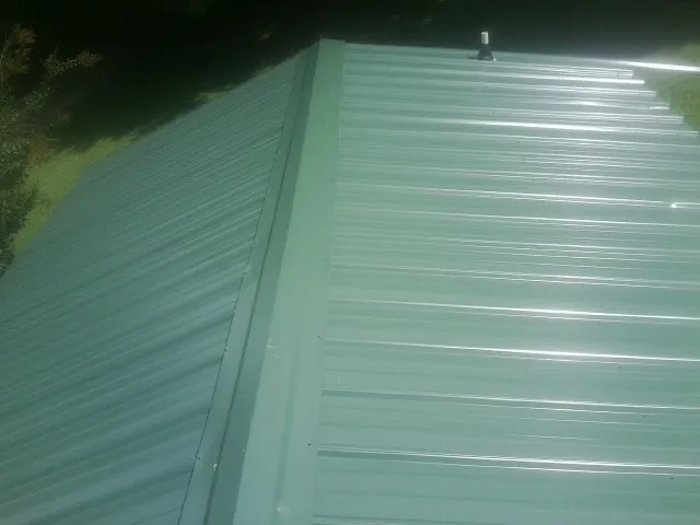 New green metal panels meeting at the ridge of a roof — Flat Roof Repair work by our crew in Idyllwild