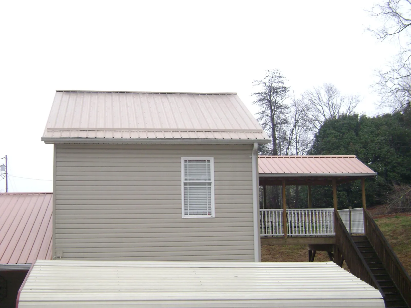 Tan metal roofs on a two story addition and attached porch, from a Roof Replacement job in Idyllwild