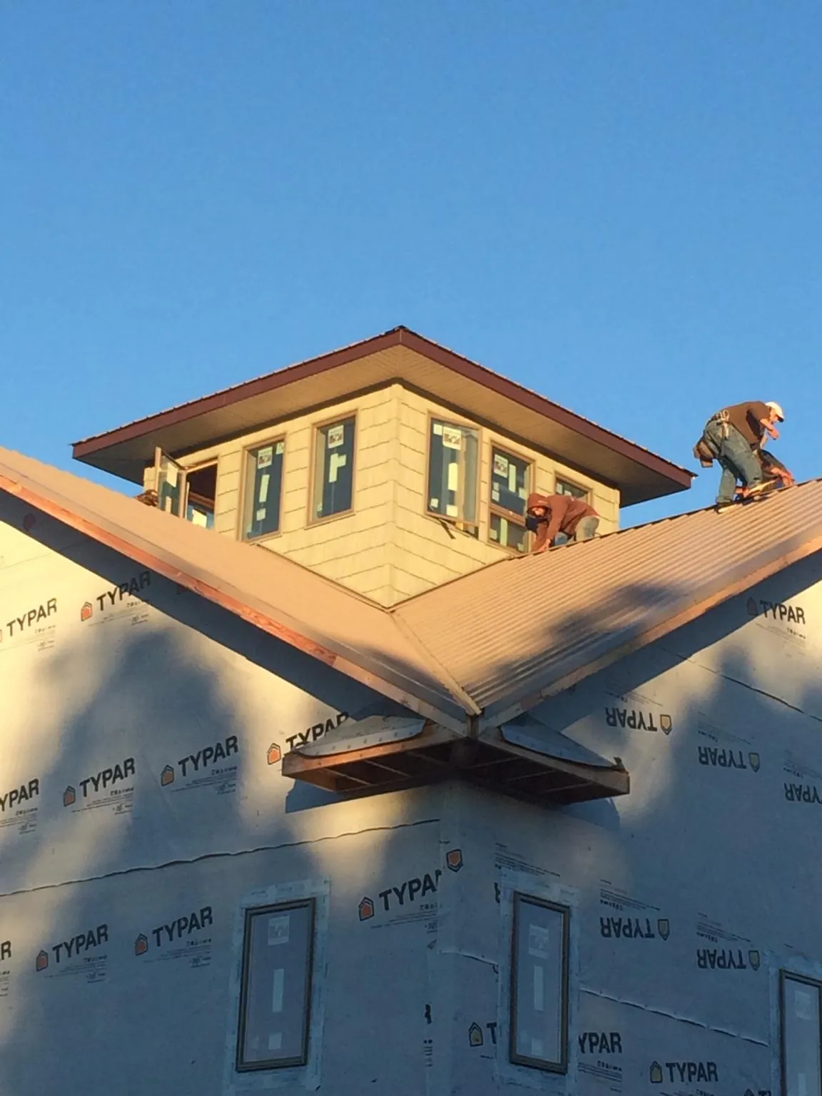 Roofers working around a rooftop cupola on a new metal roof at sunset — Roof Waterproofing in Idyllwild by Roofing Brothers